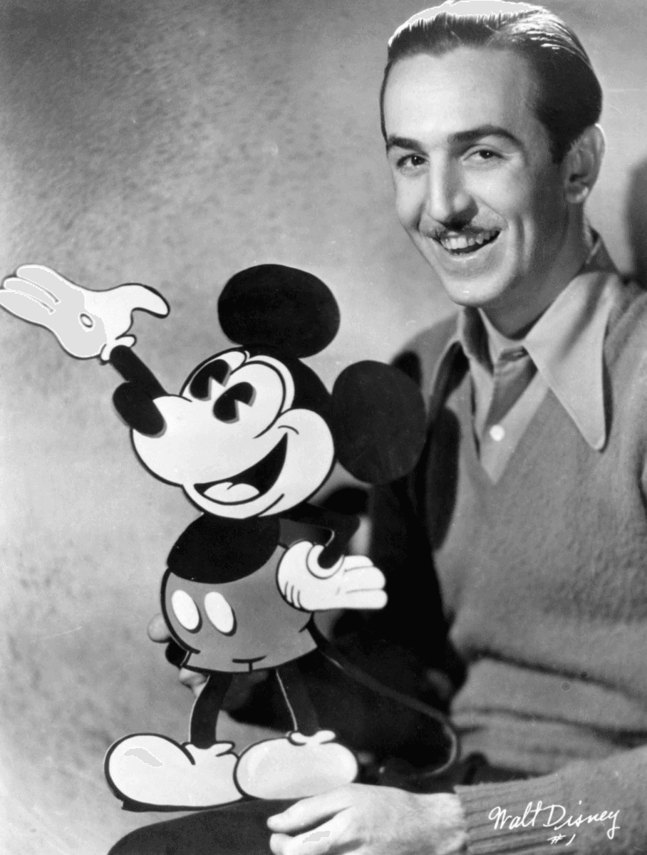 A young Walt Disney poses with Mickey Mouse