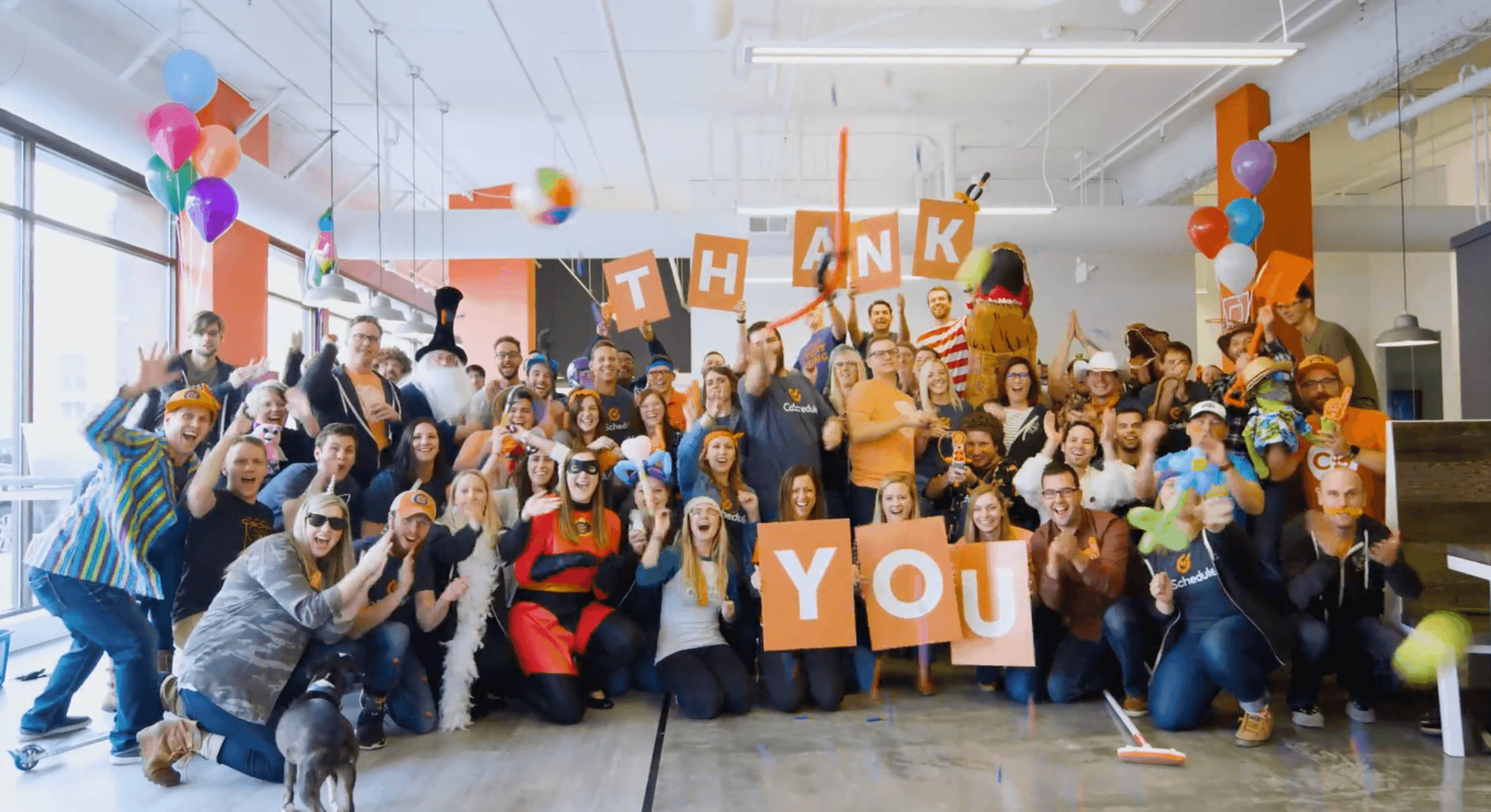 coschedule employees hold up "thank you" signs having a group picture and smiling