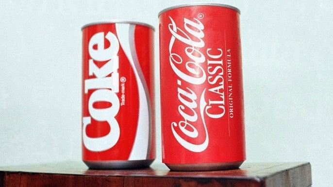 Two Coca-Cola cans sitting next to each other on a table