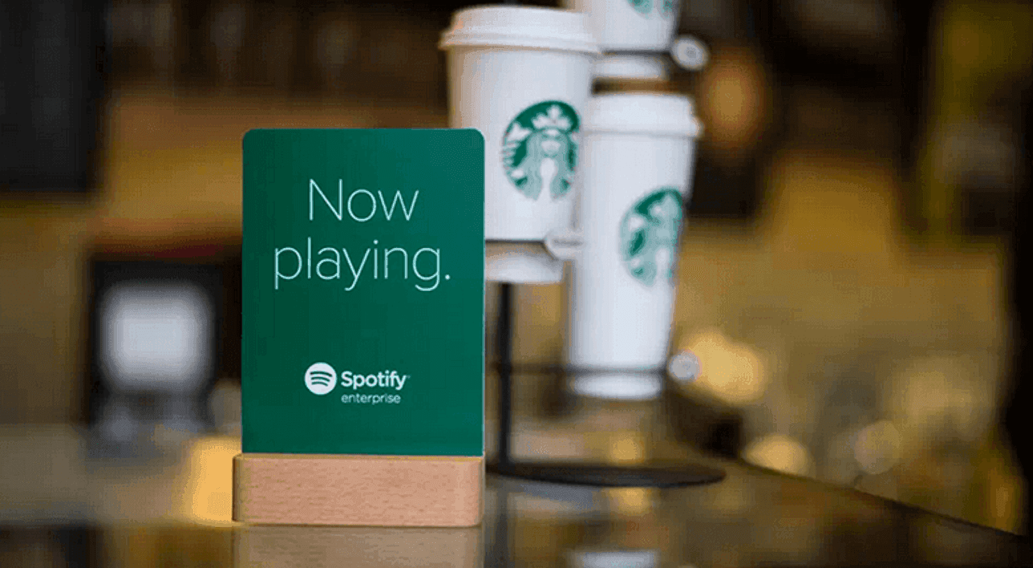 Starbucks coffee cups standing next to Spotify "Now Playing" card