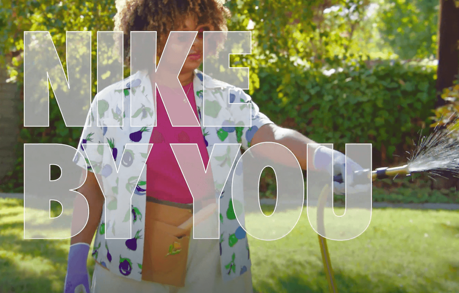 Person holding hose outdoors with "NIKE BY YOU" text in the front