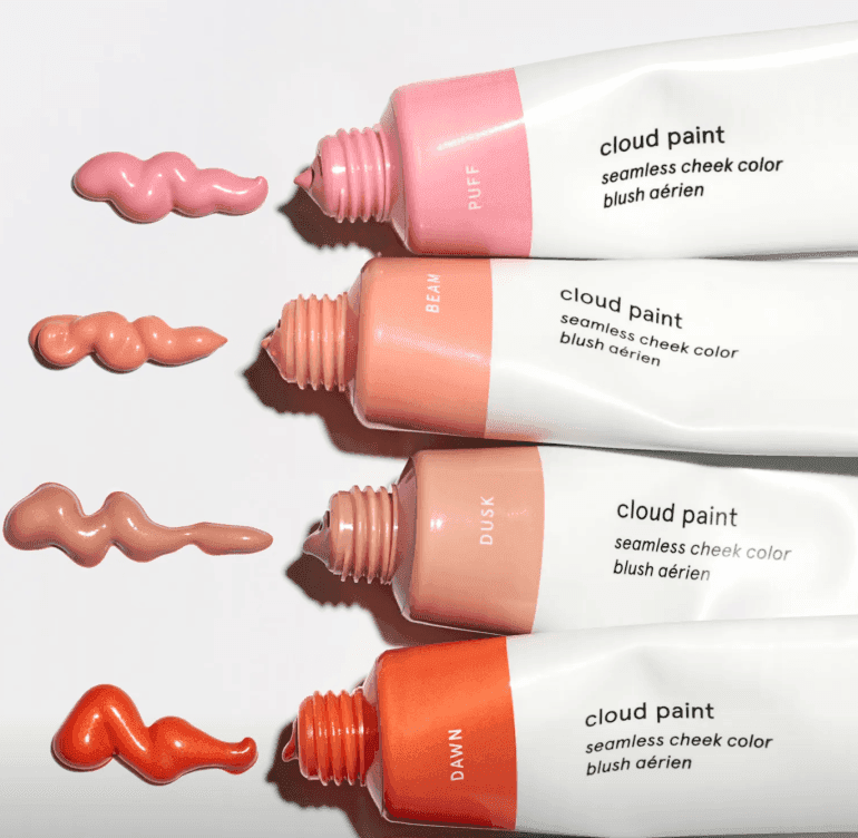 Four bottles of glossier cloud paint with paint blobs