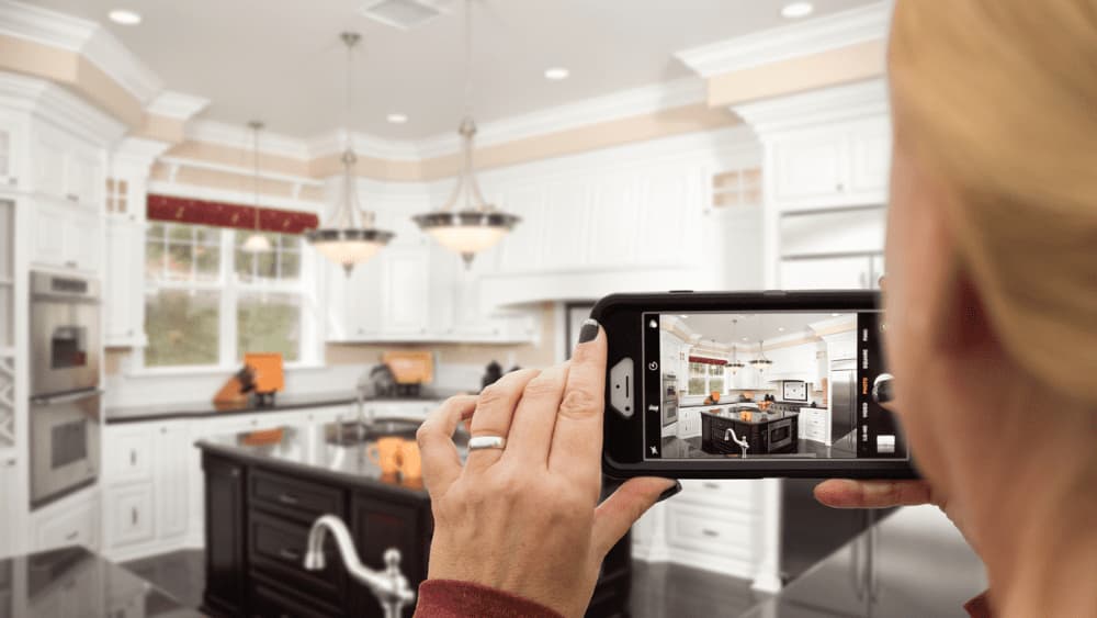 Picture of someone using a phone to take a picture of a kitchen.